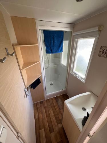 La petite salle de bains est pourvue d'une baignoire et d'une douche. dans l'établissement Mobilhome 3 chambres, à Boofzheim