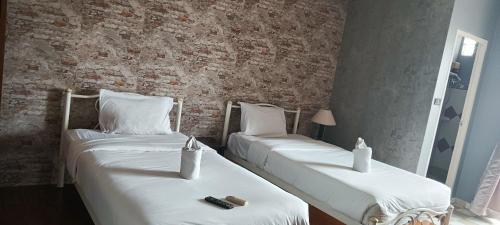 2 camas en una habitación con una pared de ladrillo en Baantalay by lily, en Nong Prue