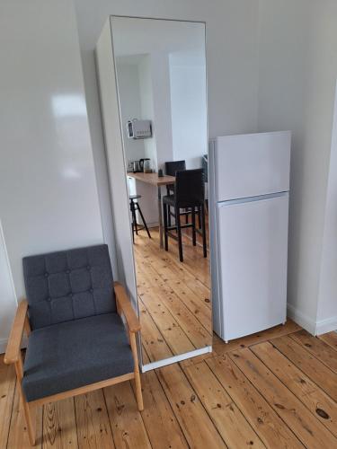 a room with a mirror and a chair and a refrigerator at Wald und Wasser in Malchow