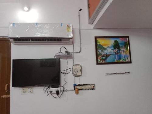 a flat screen tv hanging on a white wall at Bava guest house in Tiruvannāmalai