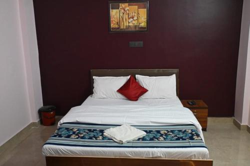 ein Schlafzimmer mit einem Bett mit einem roten Kissen in der Unterkunft Hotel The New Lake Palace in Bhopal