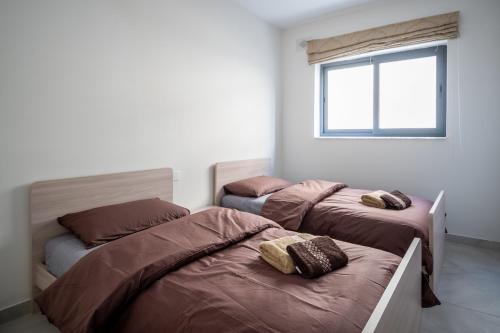 een slaapkamer met 2 bedden en een raam bij Seabreeze Luxury Apartment in St Paul's Bay