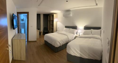 um quarto de hotel com duas camas e uma televisão de ecrã plano em لوكاندة الحصري أكتوبر motel elhosary em Cidade 6 de Outubro