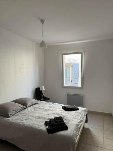 un lit dans une chambre blanche avec une fenêtre dans l'établissement Appartement tout équipé, à Les Granges-Gontardes