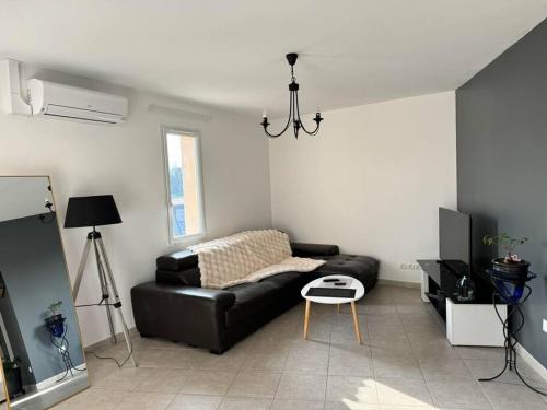 un salon avec un canapé en cuir noir et une table dans l'établissement Appartement tout équipé, à Les Granges-Gontardes