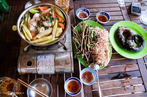 una mesa con platos de comida y un tazón de fideos en Homestay Nguyễn Hùng en Xóm Rạch Tàu