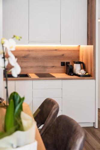 a kitchen with white cabinets and a table with a chair at Volos Inn Hotel in Volos