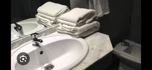 a bathroom with a sink and a pile of towels at HOTEL LA GUAREÑA in Castrillo de la Guareña