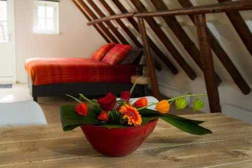 a red vase with flowers sitting on a table at Appartement Badnieuweschans in Bad-Nieuweschans