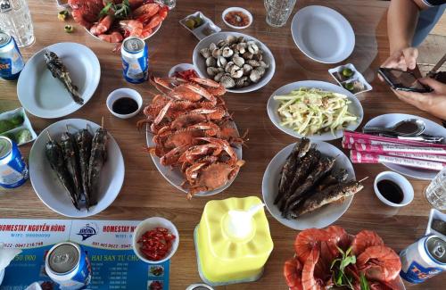 a wooden table topped with plates of seafood and food at Homestay Nguyễn Hùng in Rạch Tàu