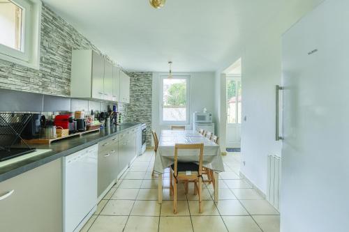 a kitchen with white cabinets and a table with chairs at Plénitude du Vexin - Grand jardin - 7 personnes in Chaumont-en-Vexin