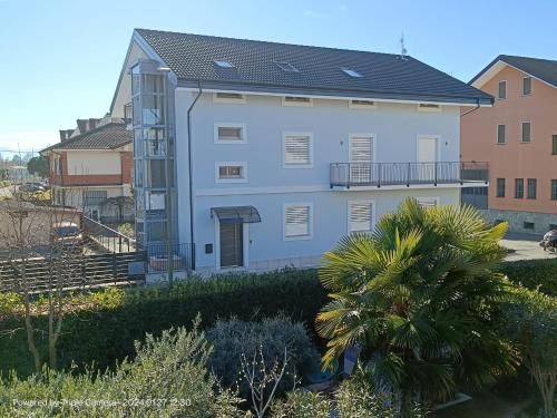 a white building with a black roof and a palm tree at Villa Mariana Bed and Breakfast in Saluzzo