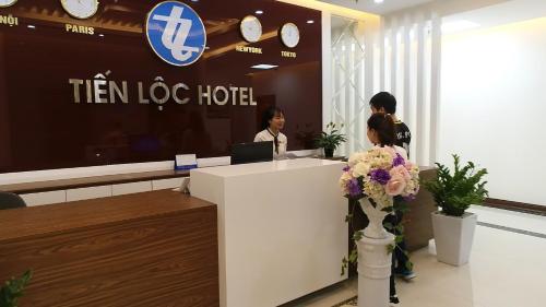 two people standing at a reception desk in a hotel at Tiến Lộc Plaza Hotel in Hà Nám