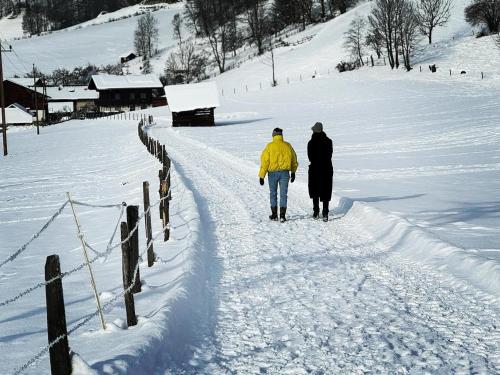 two people walking down a path in the snow at Chalet Franzi - gleich an der Piste im Gasteinertal in Dorfgastein