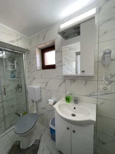 Baño blanco con lavabo y aseo en Pensiunea CAV en Novaci-Străini