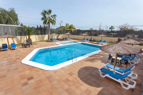 a swimming pool with chairs and umbrellas next to it at Hospedium Hotel Abril in San Juan de Alicante