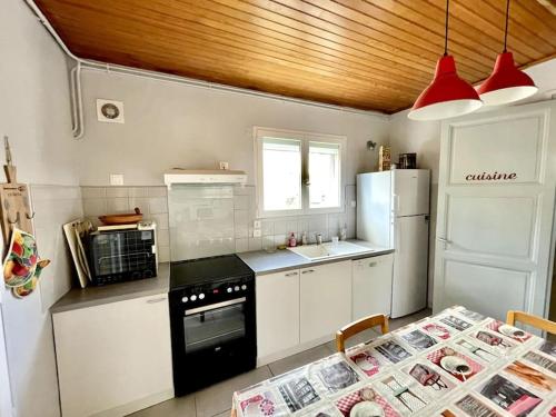 Il comprend une cuisine équipée d'une cuisinière, d'un réfrigérateur et d'une table. dans l'établissement Maison Famille 300m de l'océan, à Mimizan