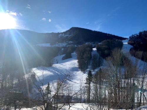 a snow covered hill with the sun shining on it at Piano Annaberg Apartments in Annaberg