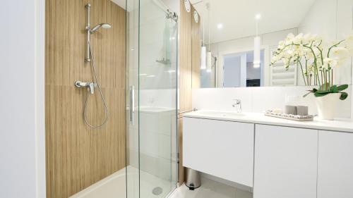 a white bathroom with a shower and a sink at Apartamenty Sun & Snow Westin House Resort in Kołobrzeg