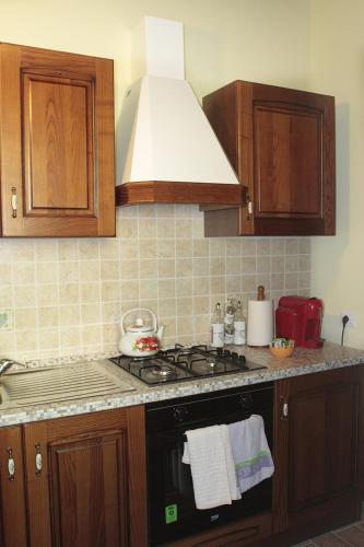 a kitchen with a stove top oven and wooden cabinets at Agriturismo Vallesessanta in Grotte di Castro