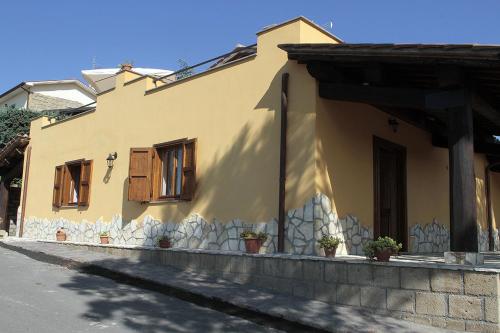 a yellow house with wooden windows on a street at Agriturismo Vallesessanta in Grotte di Castro