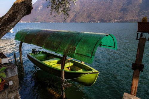 a boat with a green cover on the water at The Lake House by Quokka 360 - Lake view in Gandria village in Lugano