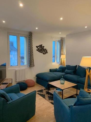 un salon avec des canapés bleus et une table dans l'établissement Appartement à Fécamp avec vue port et mer Le Sémaphore, à Fécamp