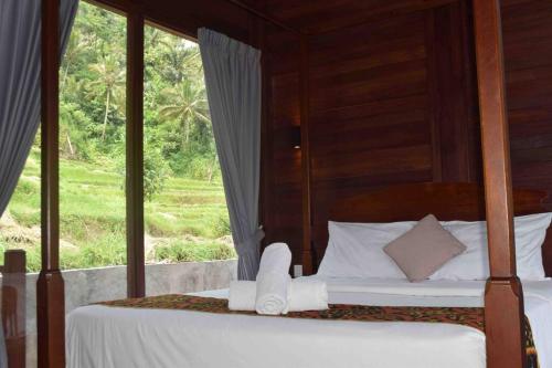 een slaapkamer met 2 bedden en een raam bij Umaduran Wooden Hut in Silebeng