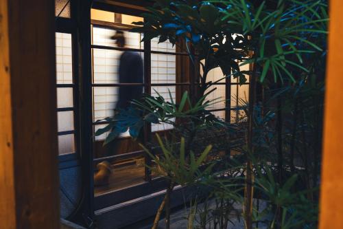 a person walking through a door with plants at Johns House じょんのやど in Himeji