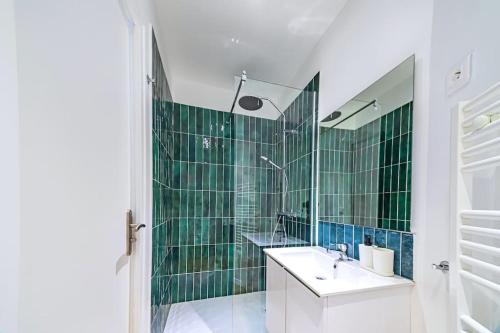 bagno con lavandino e doccia con piastrelle verdi di Appartement cosy proche de la capitale a Bagnolet