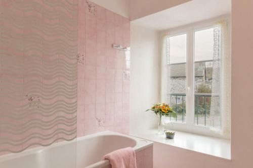 Baño rosa con bañera y ventana en Gite La Randonnée en Moudeyres