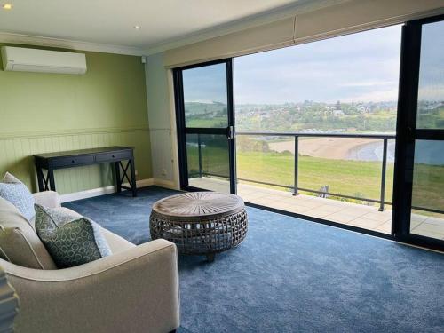 a living room with a couch and a table and windows at Kiama Ocean Retreat in Kiama