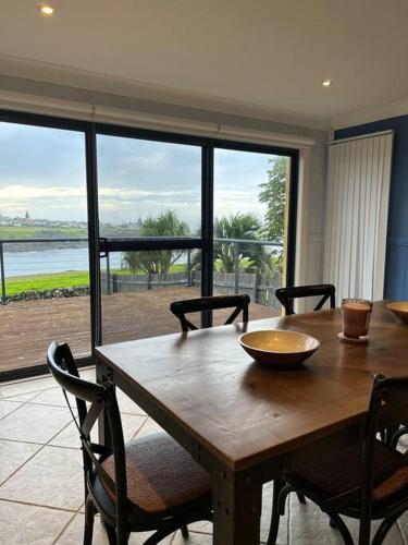 a dining room table with chairs and a large window at Kiama Ocean Retreat in Kiama
