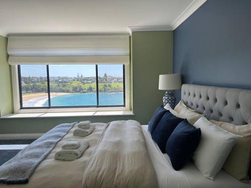 a bedroom with a large bed with a large window at Kiama Ocean Retreat in Kiama