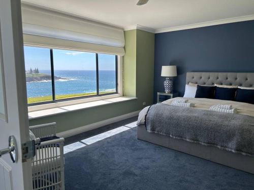 a bedroom with a large bed and a large window at Kiama Ocean Retreat in Kiama