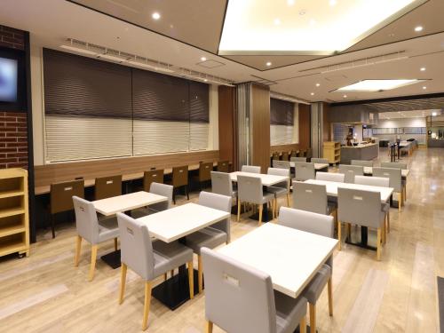 a dining room with white tables and chairs at Dormy Inn Kawasaki Natural Hot Spring in Kawasaki
