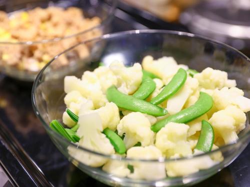 a bowl of food with green beans and cauliflower at Dormy Inn Kawasaki Natural Hot Spring in Kawasaki
