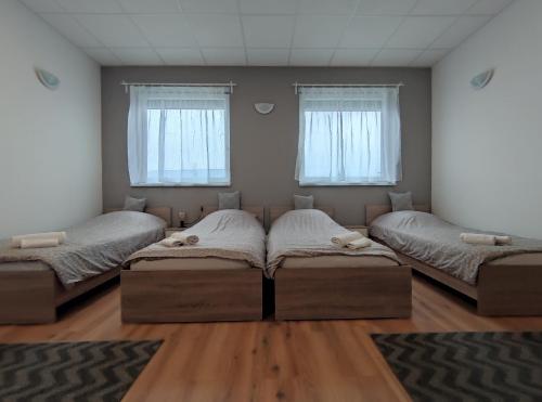 two beds in a room with two windows at Szilas Park Motel in Nagytarcsa