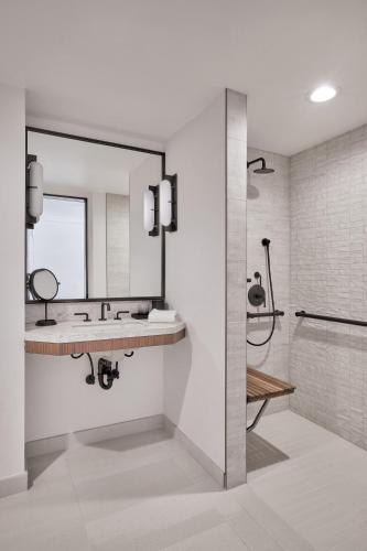 a bathroom with a sink and a mirror and a shower at The Jay, Autograph Collection in San Francisco