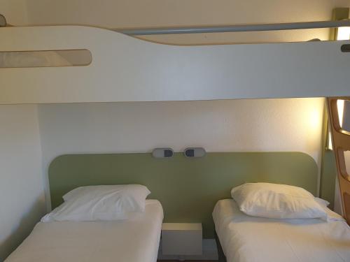 two twin beds in a room with a green headboard at Ibis Budget Roanne Hôtel in Roanne