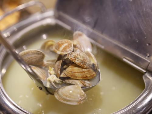 a spoon full of clams in a pot of water at Dormy Inn Kawasaki Natural Hot Spring in Kawasaki
