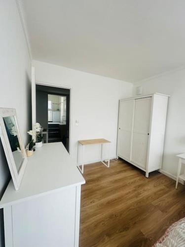 Cette chambre blanche dispose d'une table et d'une armoire blanches. dans l'établissement Le Cosy au cœur de Brétigny, à Brétigny-sur-Orge