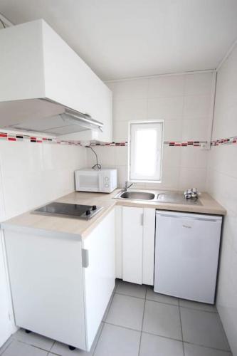 une petite cuisine avec des armoires blanches et un évier dans l'établissement Le Cosy au cœur de Brétigny, à Brétigny-sur-Orge