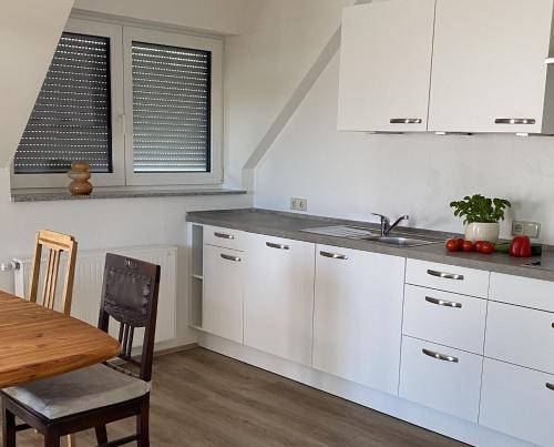 a kitchen with white cabinets and a wooden table at Ferienwohnung II in Schnelldorf