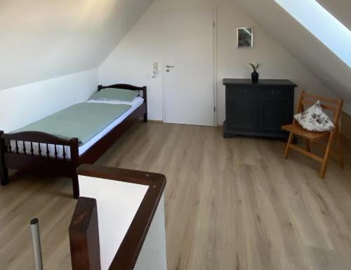 a room with a bed and a chair in a attic at Ferienwohnung II in Schnelldorf