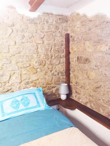 a bedroom with a stone wall with a bed and a lamp at Villa La Pineta in Umbertide