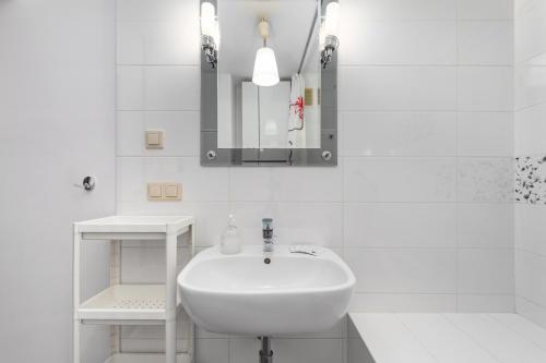 a white bathroom with a sink and a mirror at Miedziana 14 by Homeprime in Warsaw