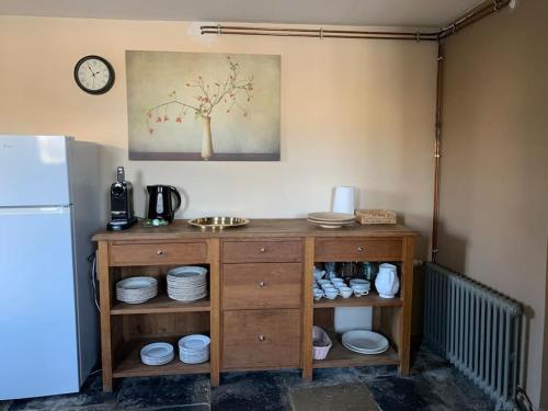 a kitchen with a wooden cabinet with plates and a clock at Gîte de groupe agritourisme 3 gîtes mitoyens 25 couchages Convivialité et intimité in Lingèvres
