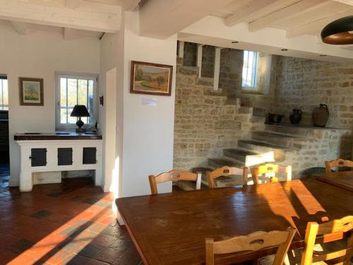 a dining room with a wooden table and a brick wall at Gîte de groupe agritourisme 3 gîtes mitoyens 25 couchages Convivialité et intimité in Lingèvres