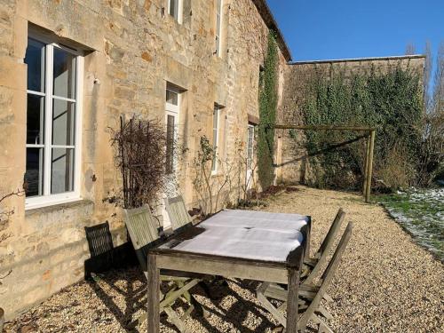 a picnic table in front of a brick building at Gîte de groupe agritourisme 3 gîtes mitoyens 25 couchages Convivialité et intimité in Lingèvres